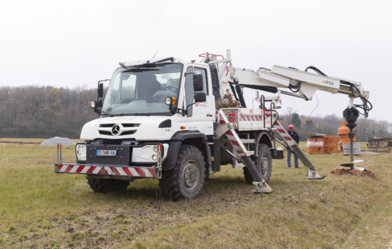 Image d'un UNIMOG U530 carrossé avec une grue RISA 74TA30, capacité de levage 7400kg à 3 mètres de l'axe de la grue. Stabilisateurs panthographiques, moteur de forage POCLAIN MS35, tarière désagrégatrice, radio-commande télécommande pour la commande du fonctionnement de la grue.